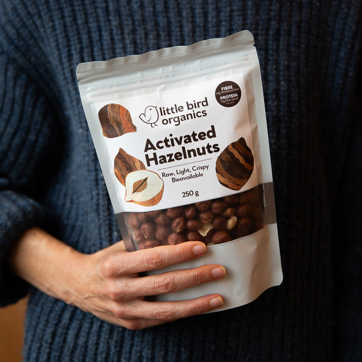 Person holding a package of Little Bird Organics Activated Hazelnuts.